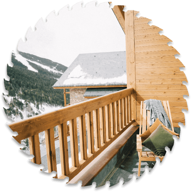 A wooden deck with snow on the mountain behind it.